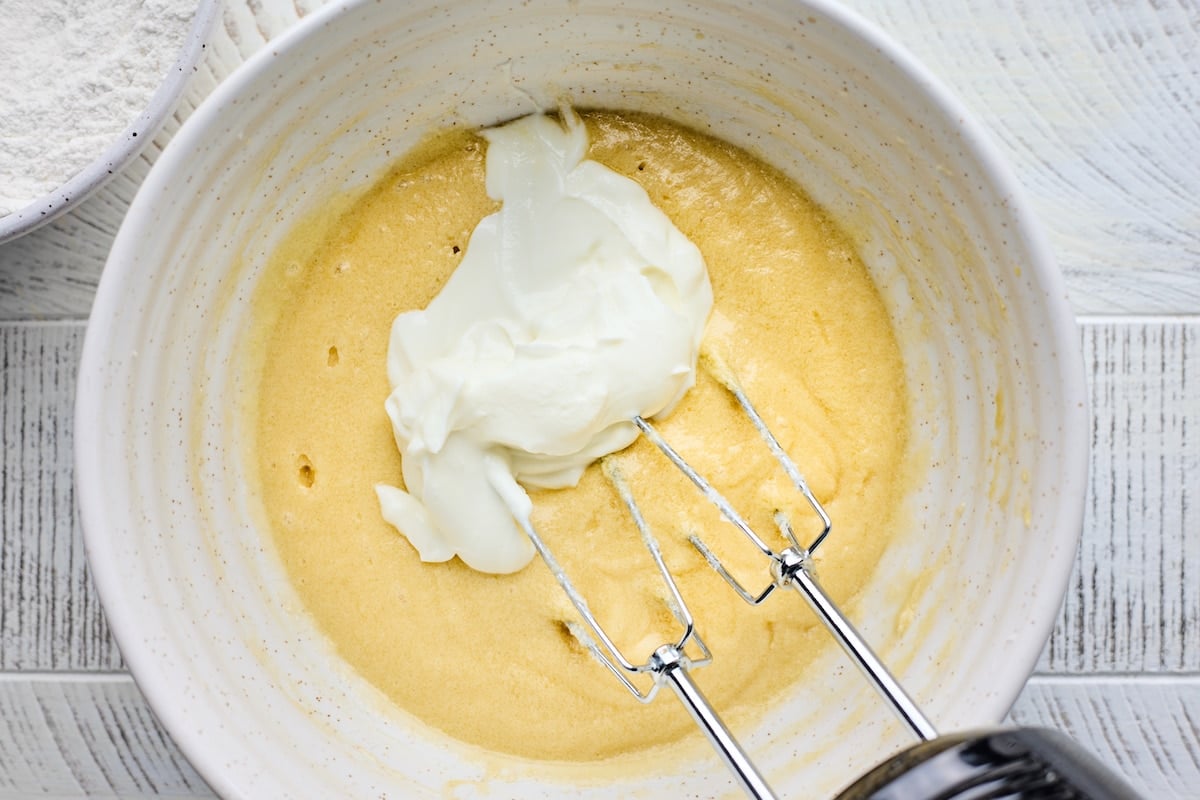 muffin batter in mixing bowl with Greek yogurt and hand mixer. 