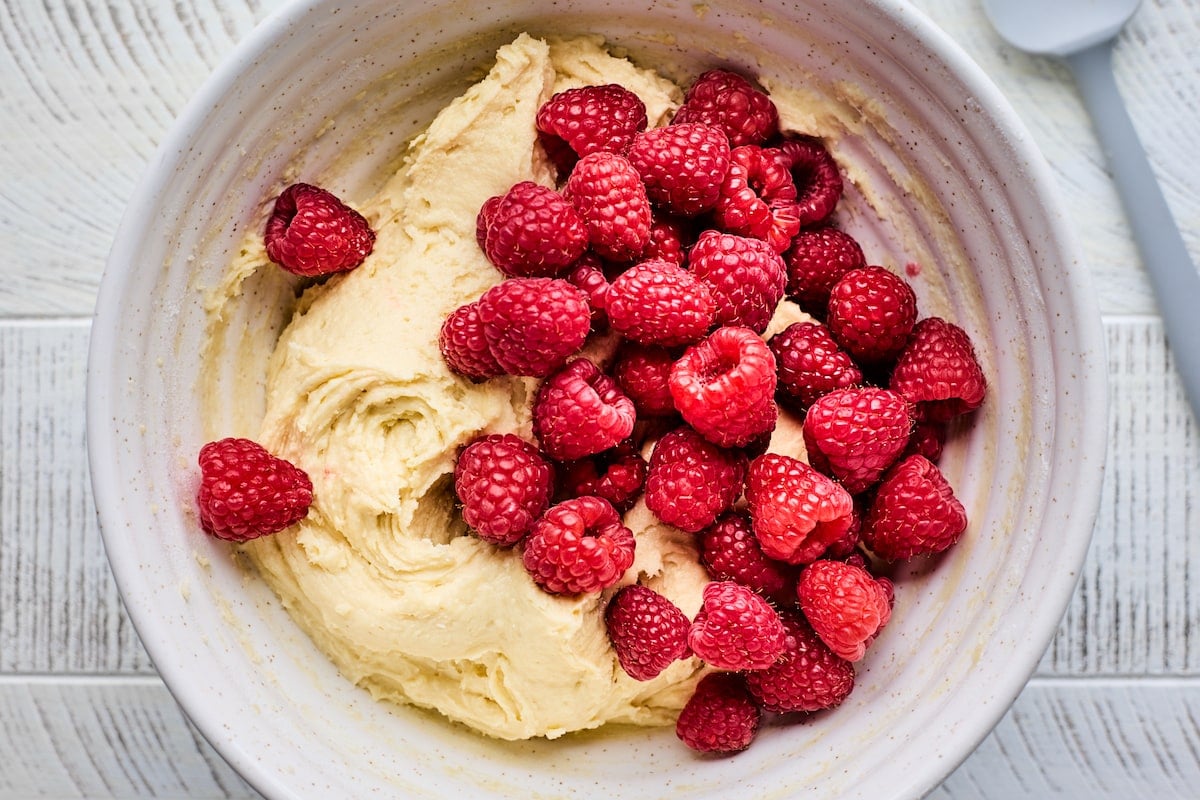 muffin batter in mixing bowl with fresh raspberries. 
