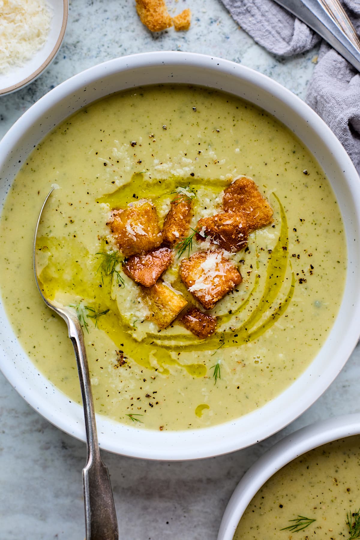 zucchini soup in bowl with croutons and spoon. 