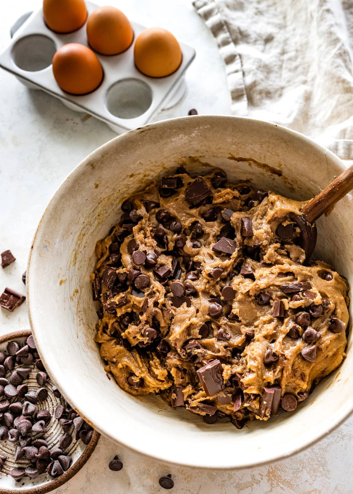 brown butter chocolate chip cookie bar dough being mixed in bowl with wooden spoon. 