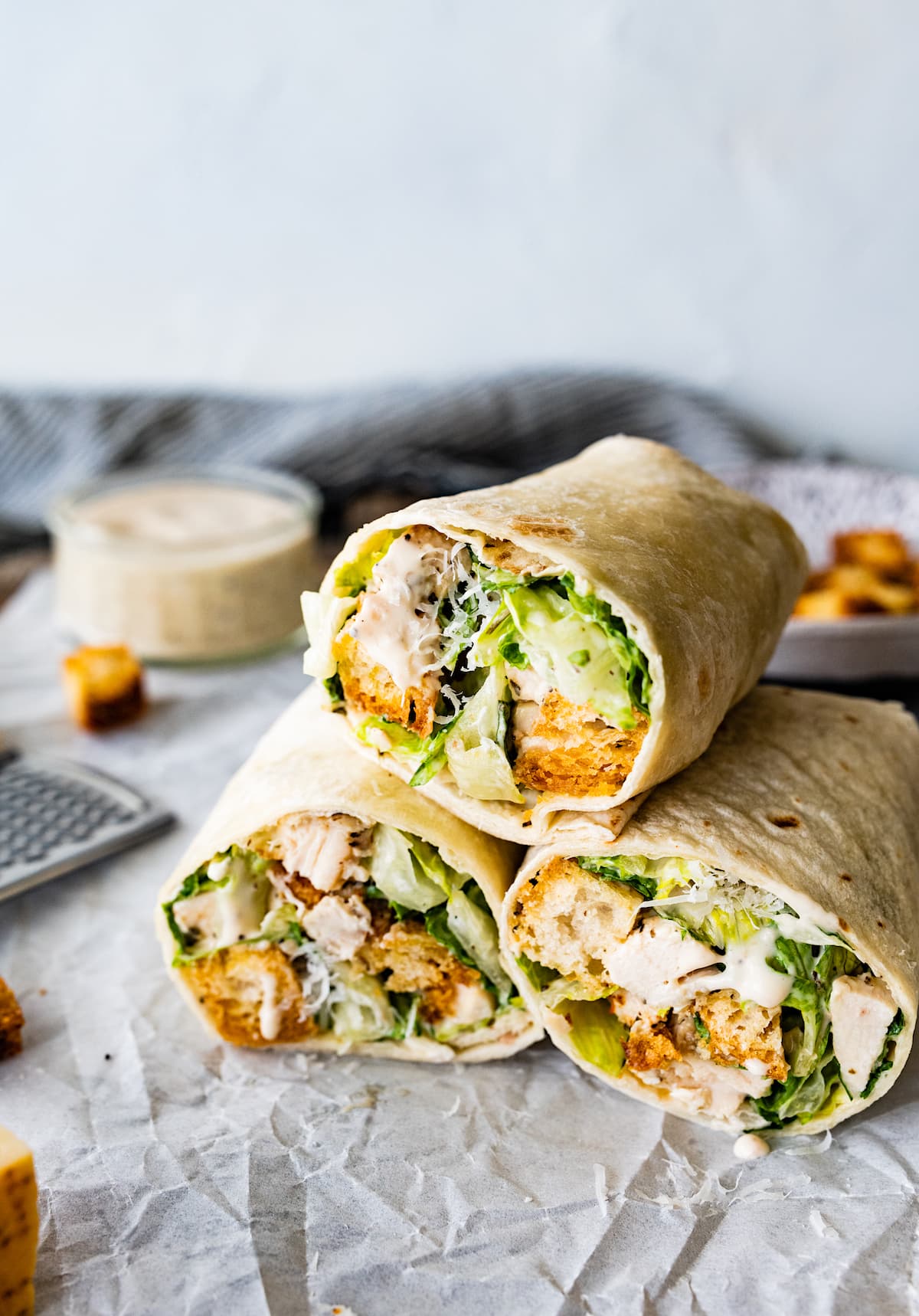 chicken caesar wraps stacked on parchment paper. 