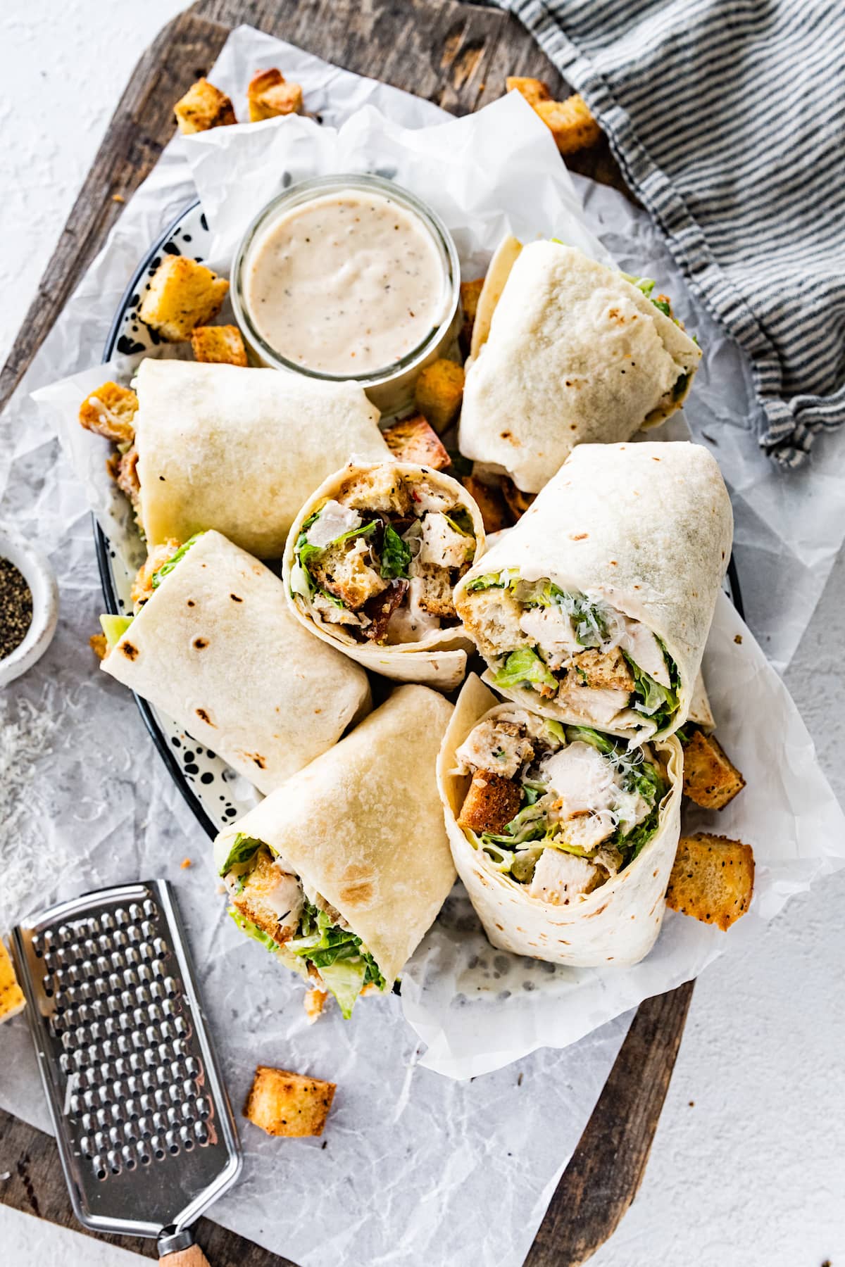 chicken caesar salad wraps cut in half in serving platter with homemade croutons. 