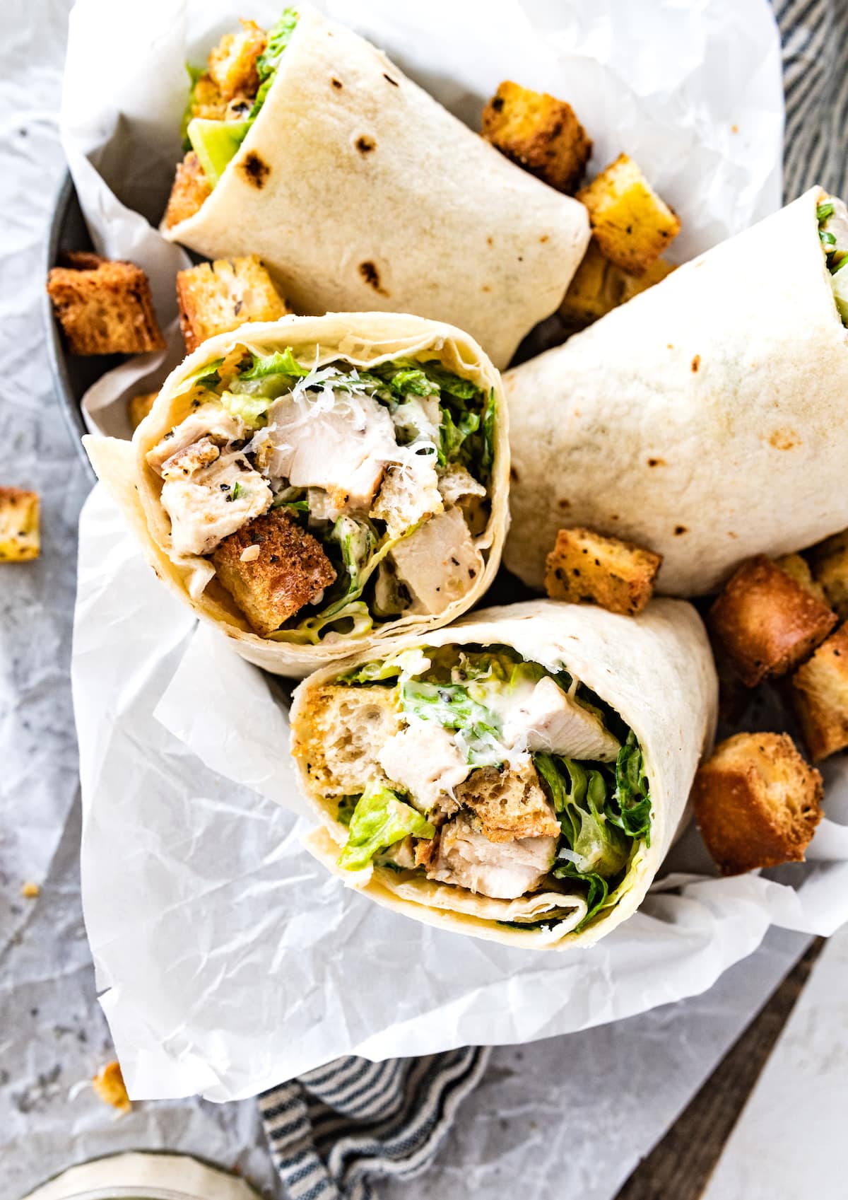 chicken caesar wraps cut in half in bowl with croutons. 