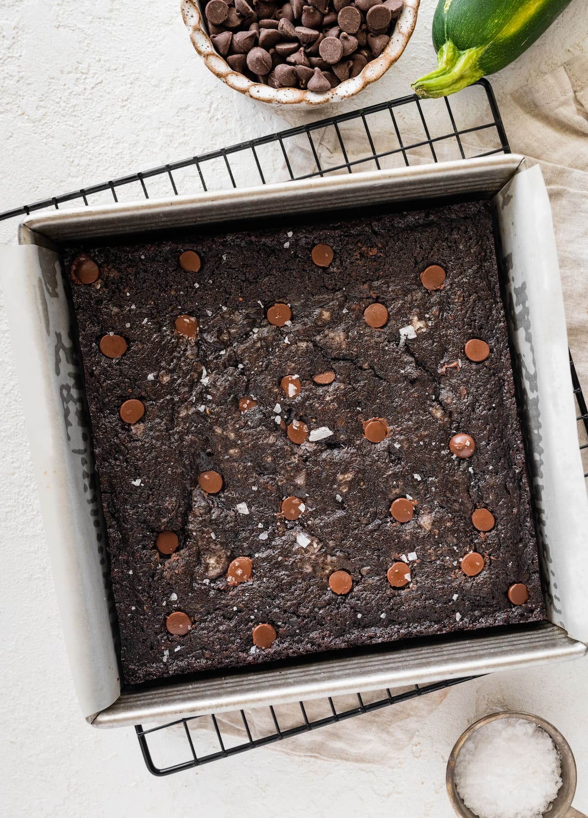 chocolate zucchini snack cake with chocolate chips and flaky sea salt cooling on wrack. 