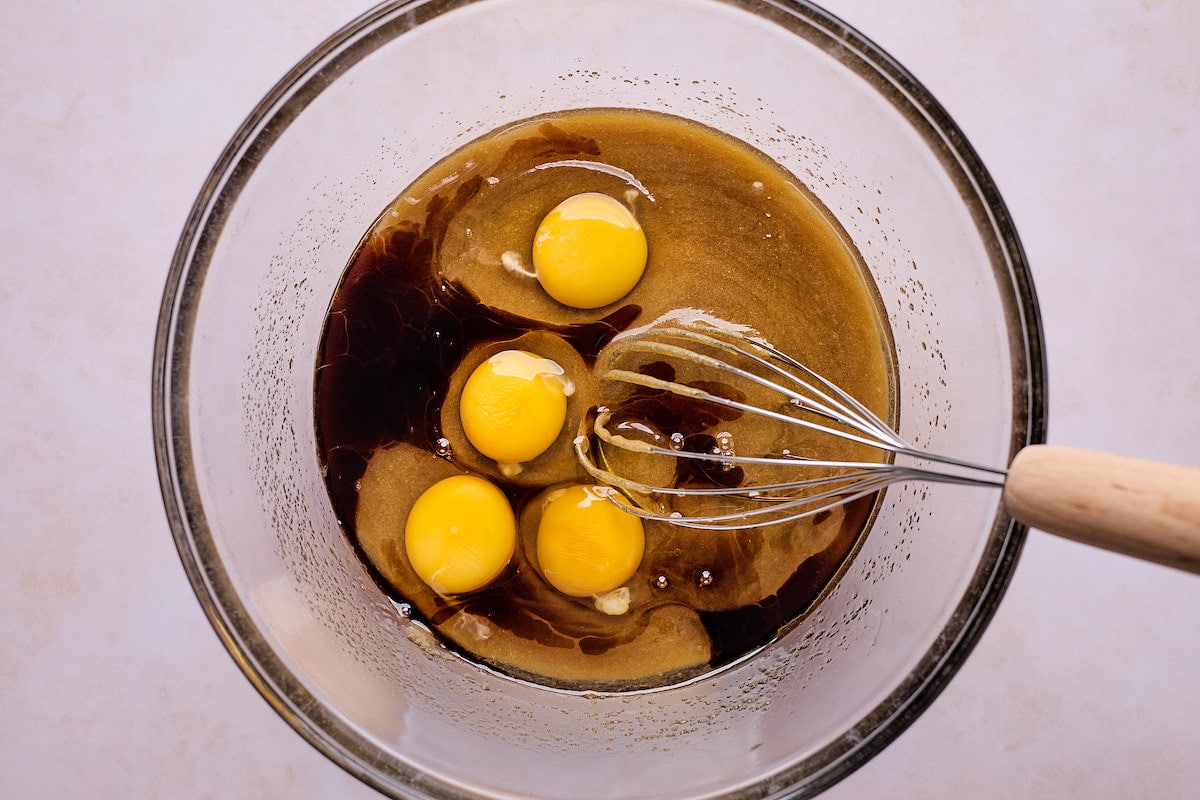 eggs being whisked with sugars in mixing bowl to make raspberry brownies. 