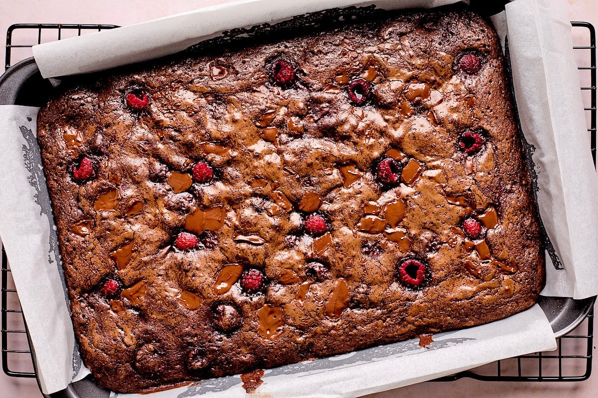 baked raspberry brownies in pan with parchment paper. 