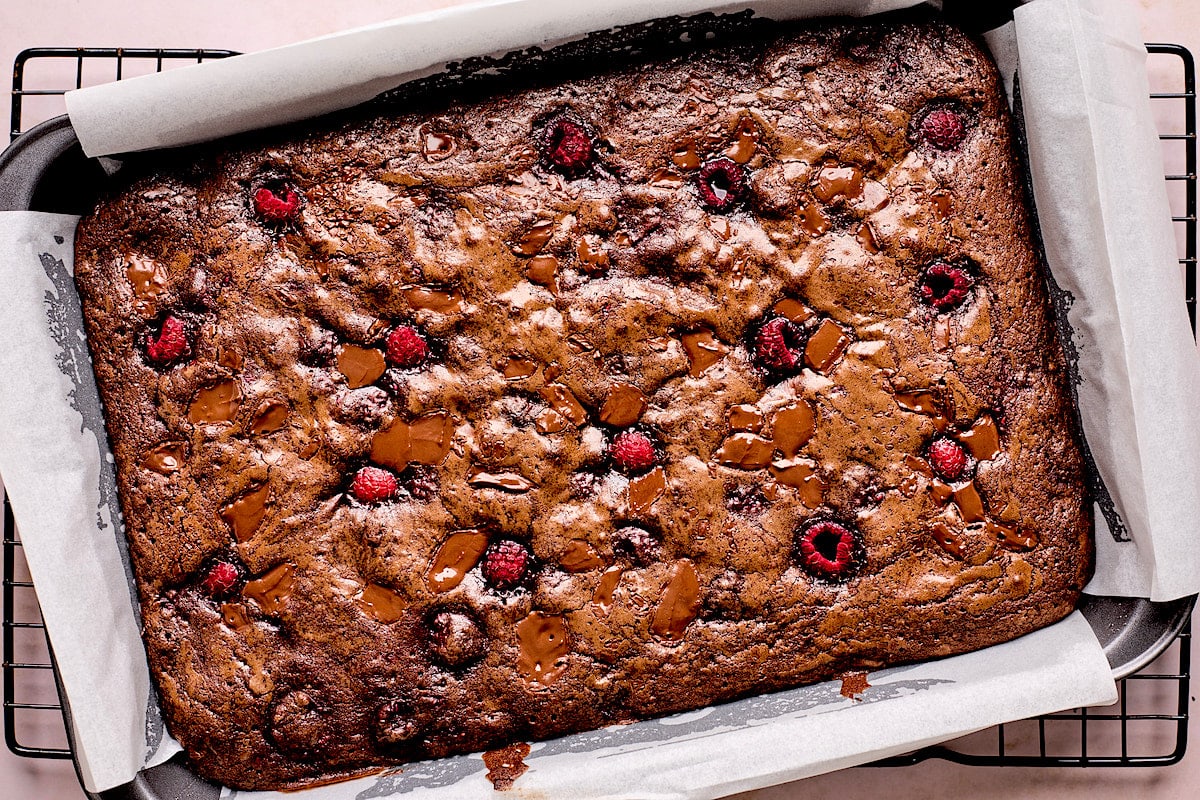 baked raspberry brownies in pan with parchment paper. 