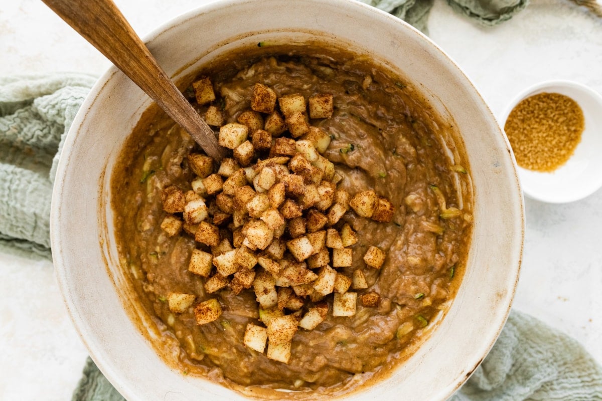 apple zucchini bread batter in mixing bowl with wooden spoon. 