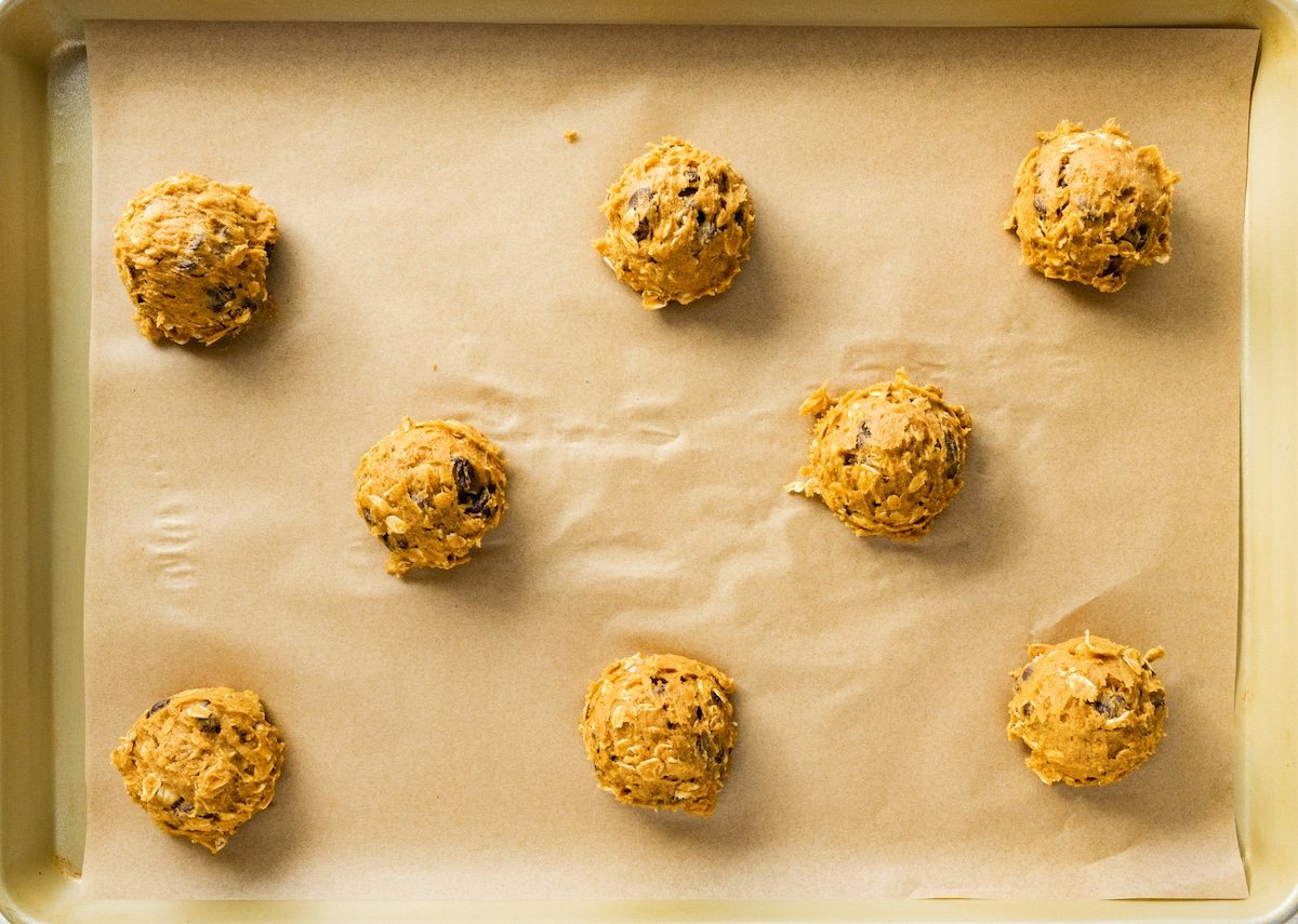 pumpkin oatmeal chocolate chip cookie dough on baking sheet with parchment paper. 
