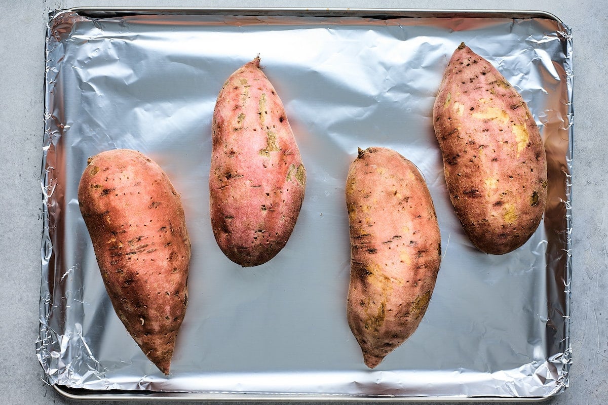 sweet potatoes on baking sheet lined with aluminum foil. 