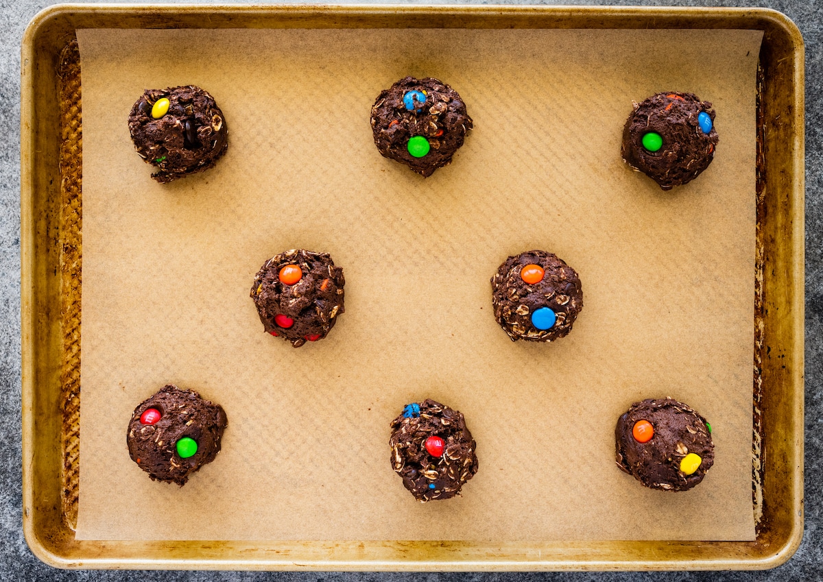 monster cookie dough balls scooped onto baking sheet with parchment paper. 