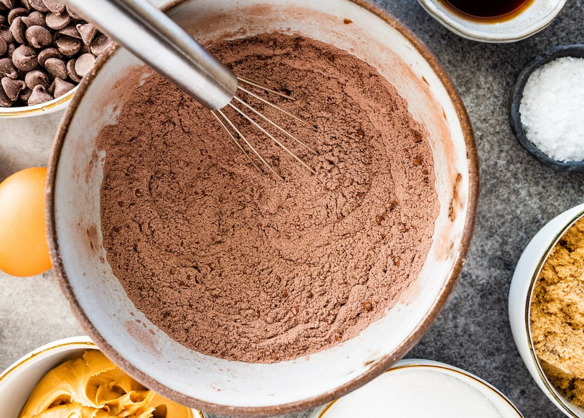 flour, cocoa, baking soda, and salt being whisked together in bowl. 