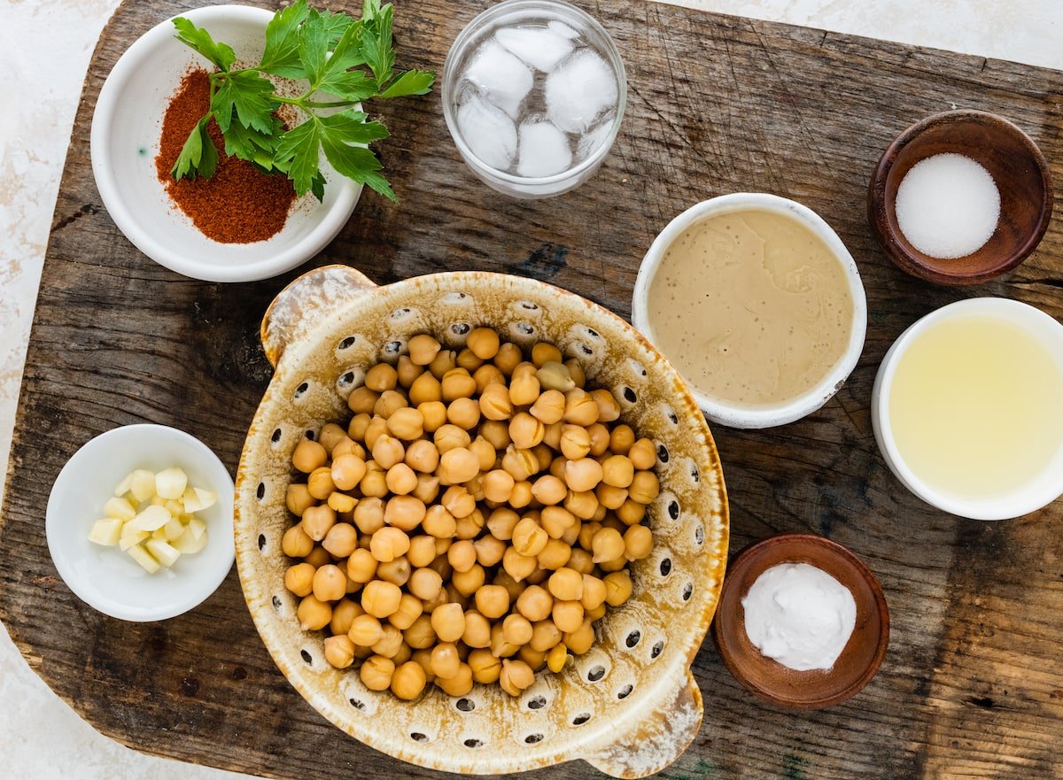 chickpeas in bowl with ingredients to make hummus. 