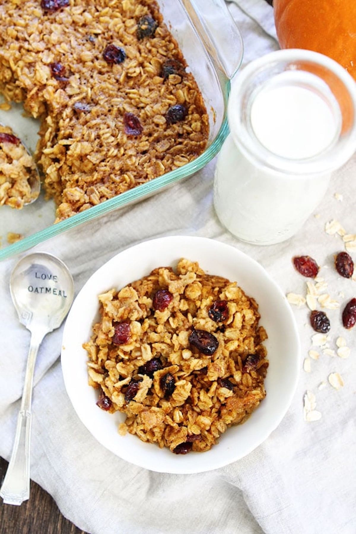 pumpkin baked oatmeal in bowl with glass jar of milk and spoon. 