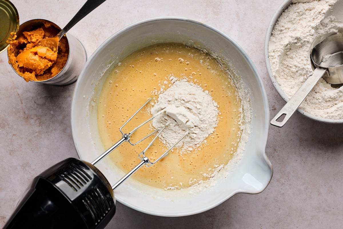 pumpkin bundt cake batter being mixed with hand mixer in bowl. 