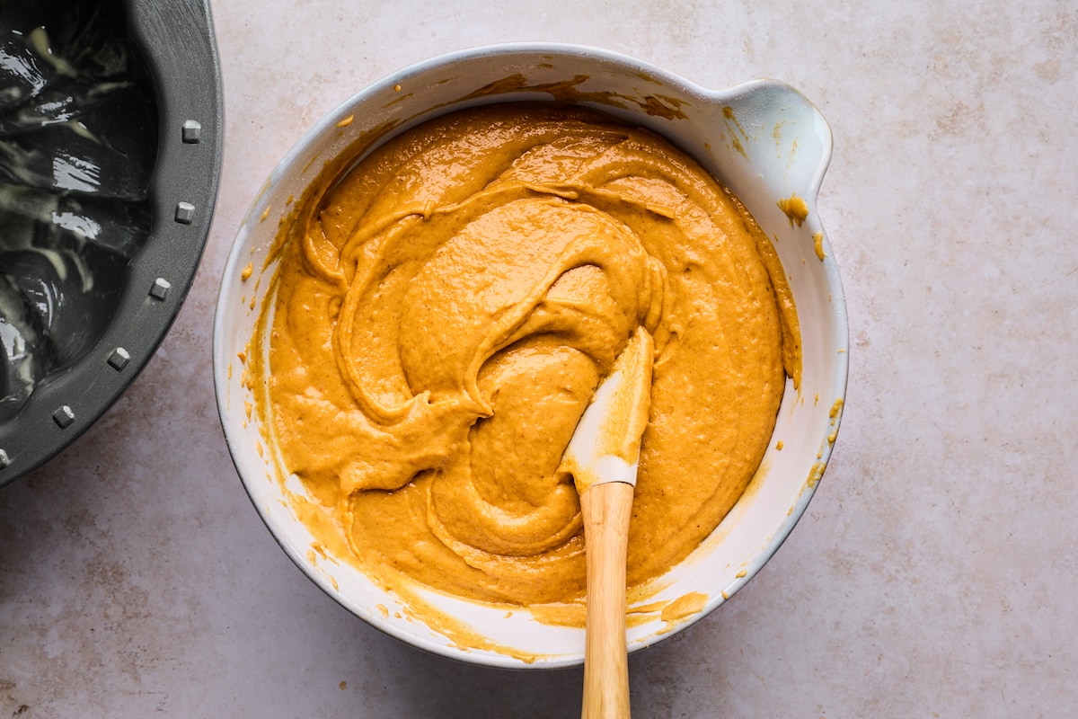 pumpkin bundt cake batter in mixing bowl with spatula. 