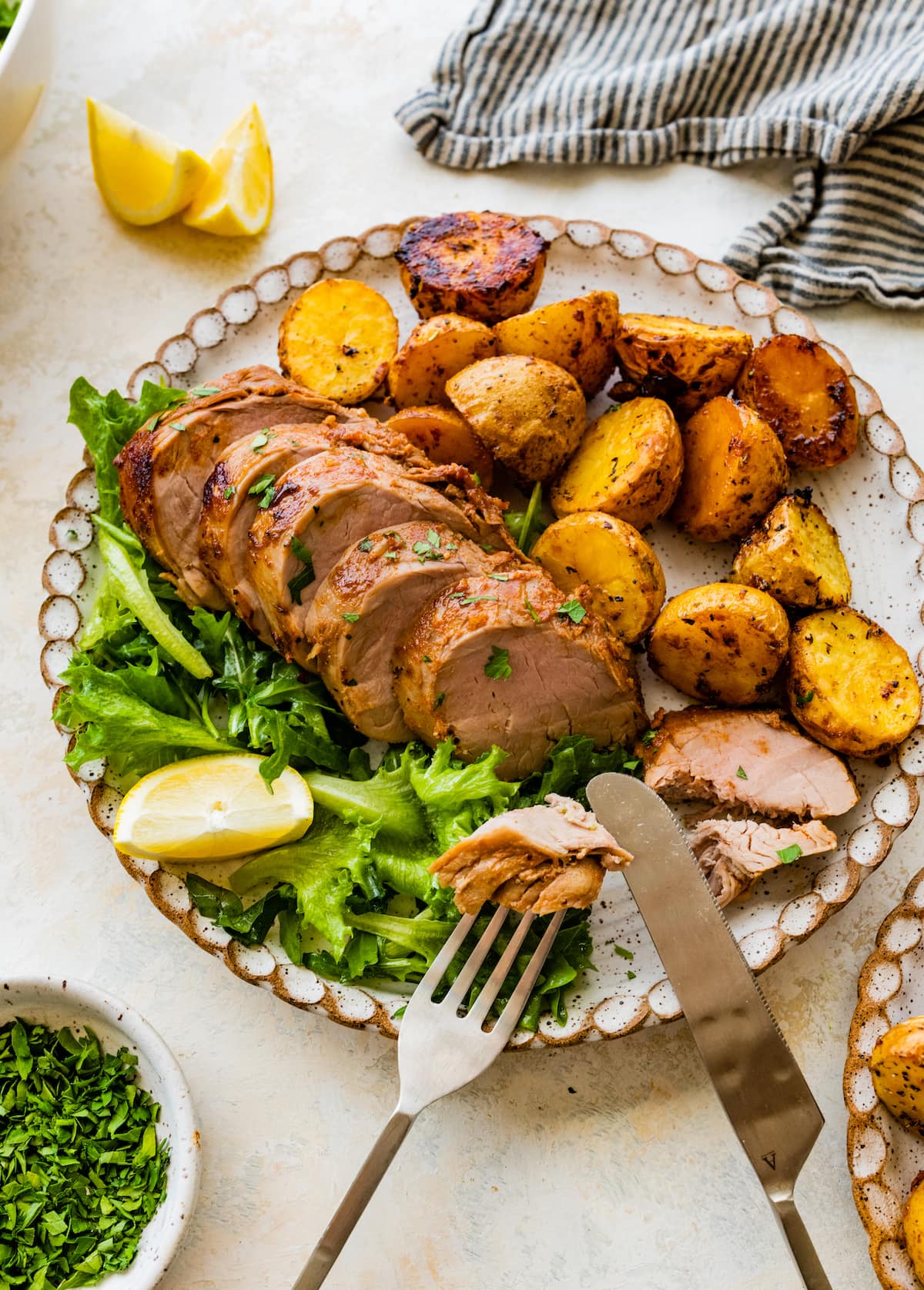 juicy pork tenderloin slices on plate with potatoes and salad. 