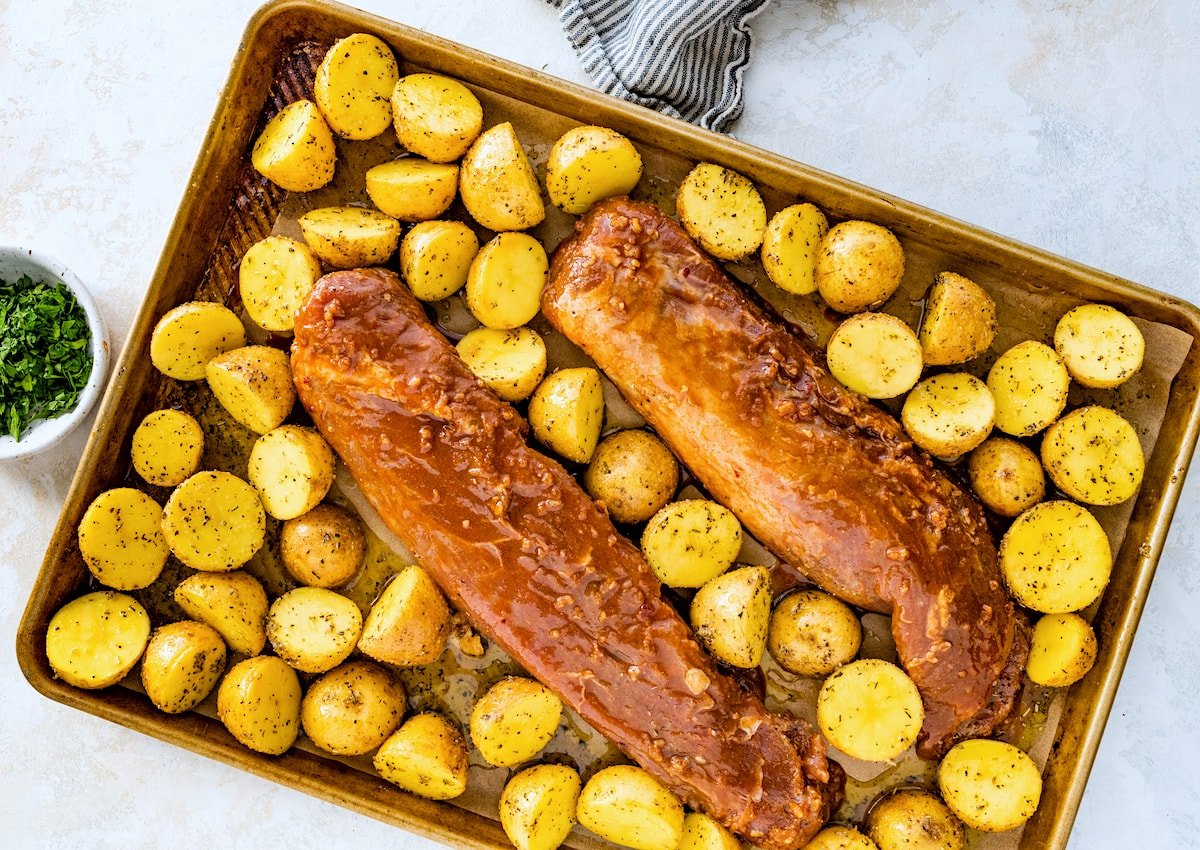 pork tenderloins on sheet pan with seasoned potatoes. 