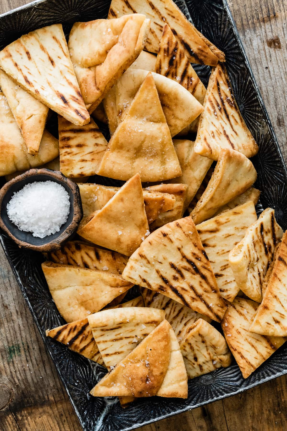 homemade pita chips on tray with salt. 