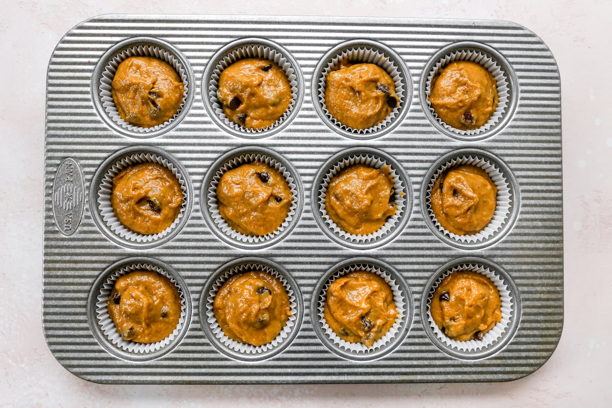 pumpkin chocolate chip muffin batter in muffin pan. 