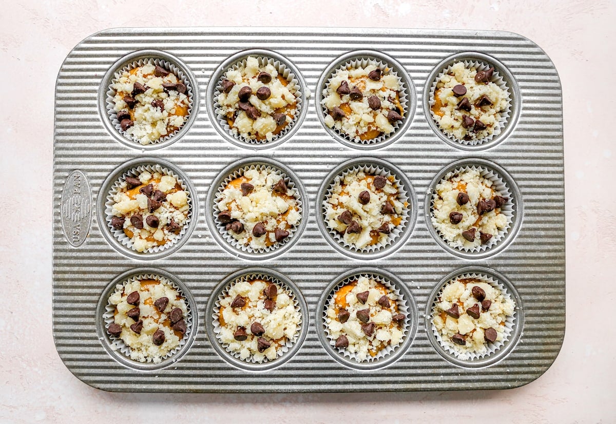 pumpkin chocolate chip muffin batter with streusel topping in muffin pan. 