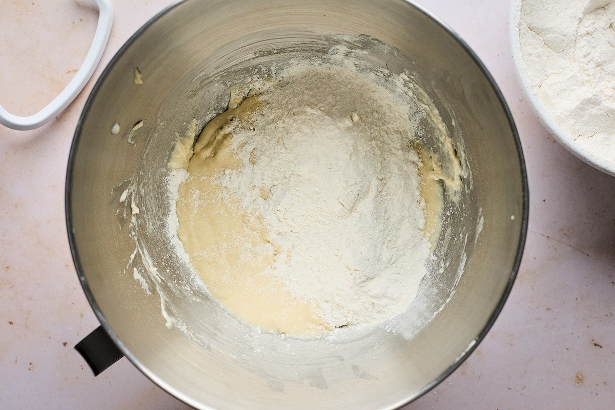 adding flour to dinner roll dough in mixing bowl. 