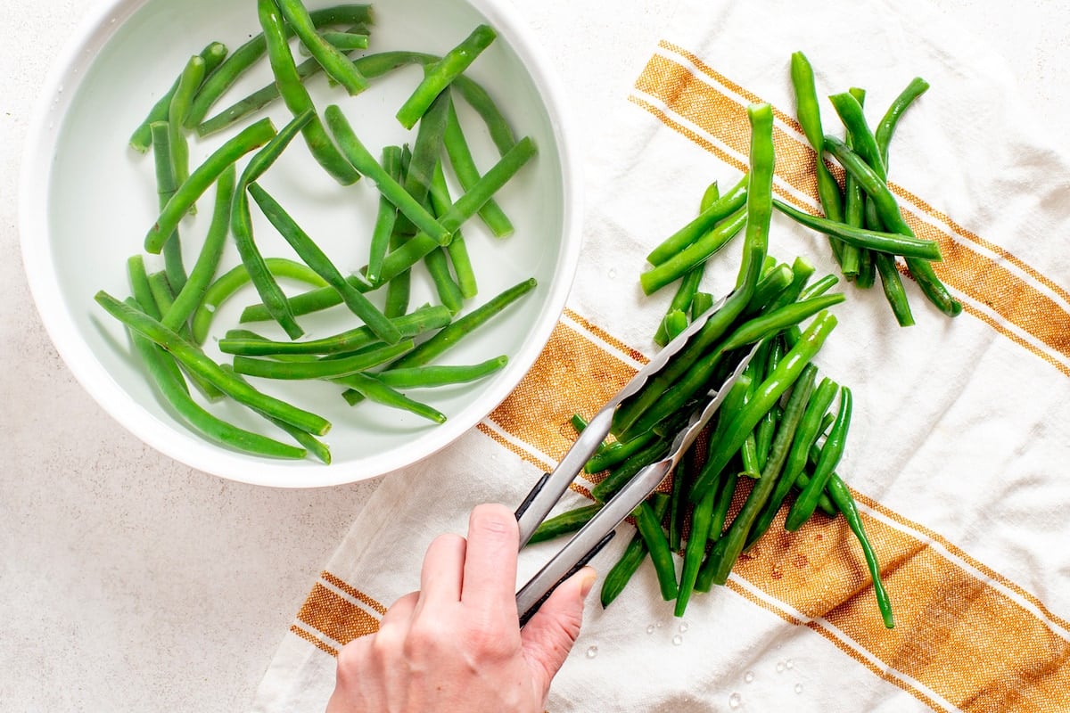 green beans being removed from ice bath with tongs. 