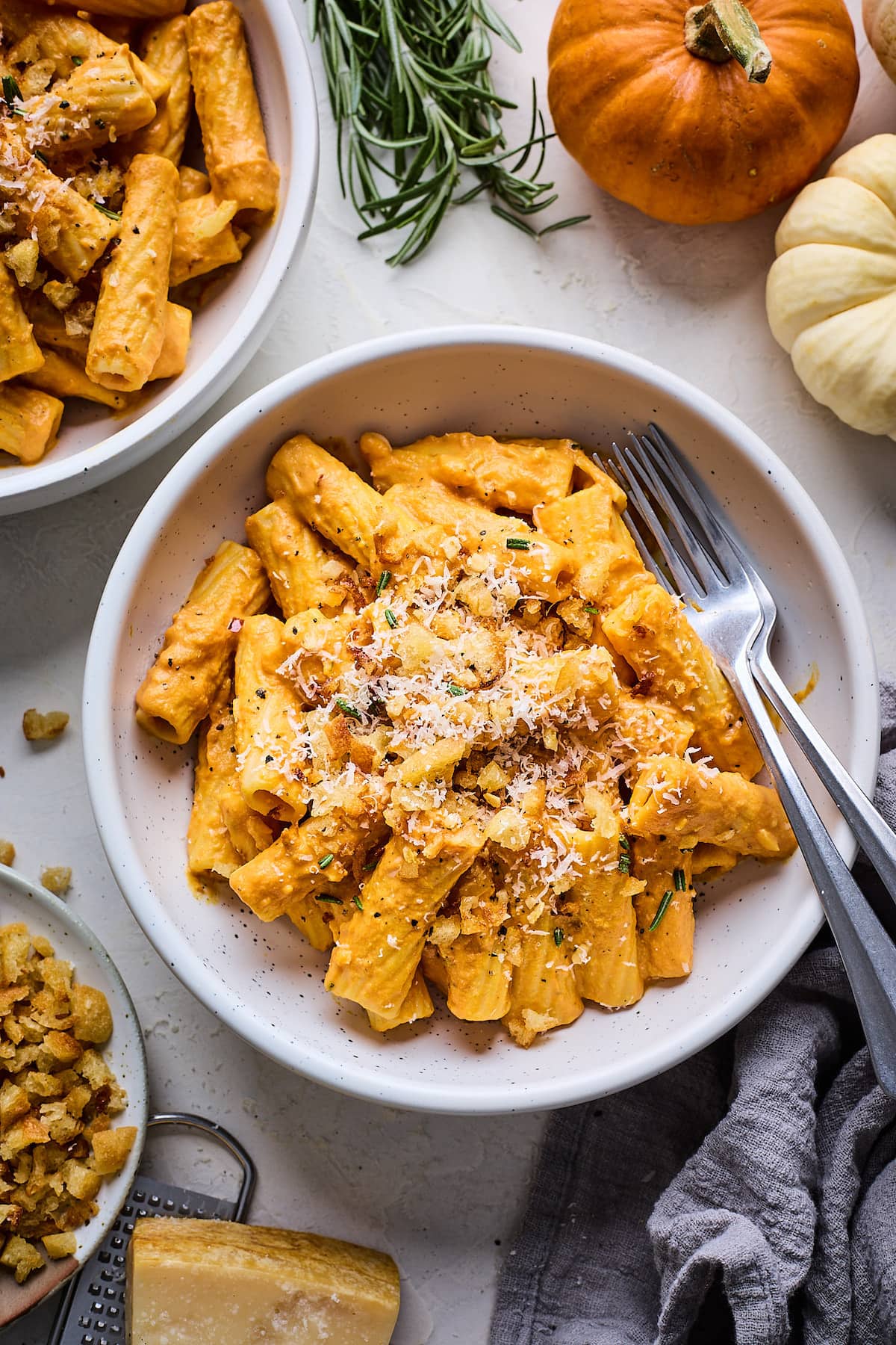 pumpkin pasta with toasted breadcrumbs and Parmesan cheese in bowl with forks. 