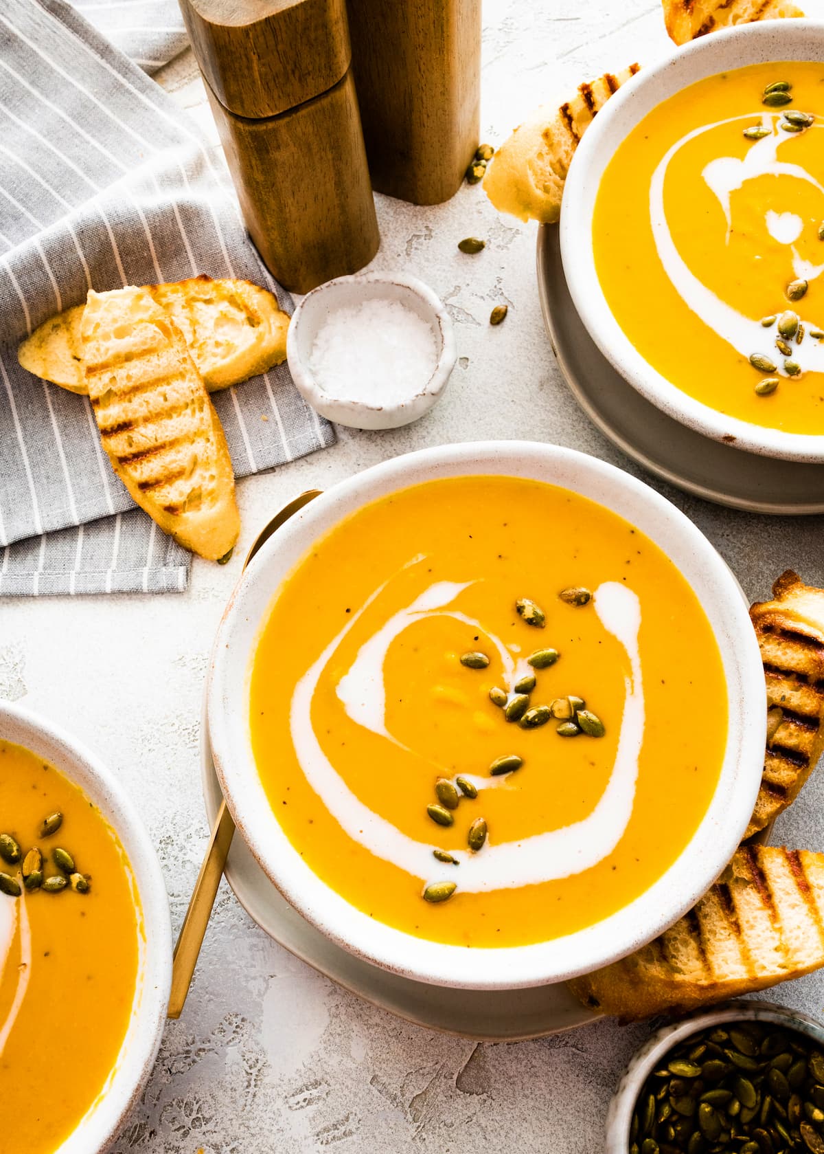 bowls of roasted butternut squash pear ginger soup in bowls with grilled bread. 