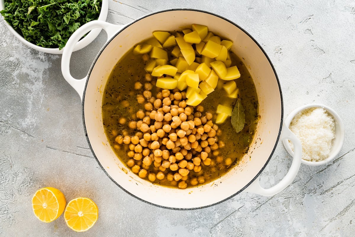 chickpeas, potatoes, broth, spices, and bay leaf in pot to make chickpea soup.