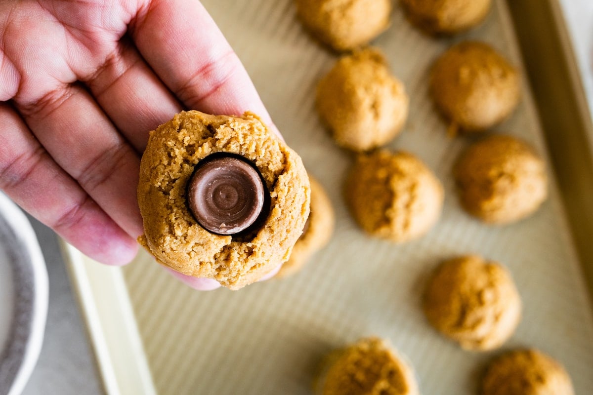 ginger molasses cookie dough being wrapped around a Rolo candy. 