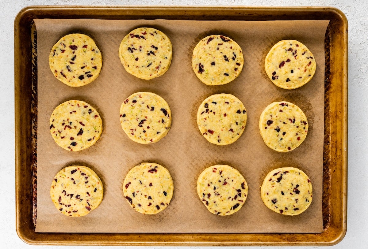 cranberry orange pistachio shortbread cookies on baking sheet with parchment paper. 