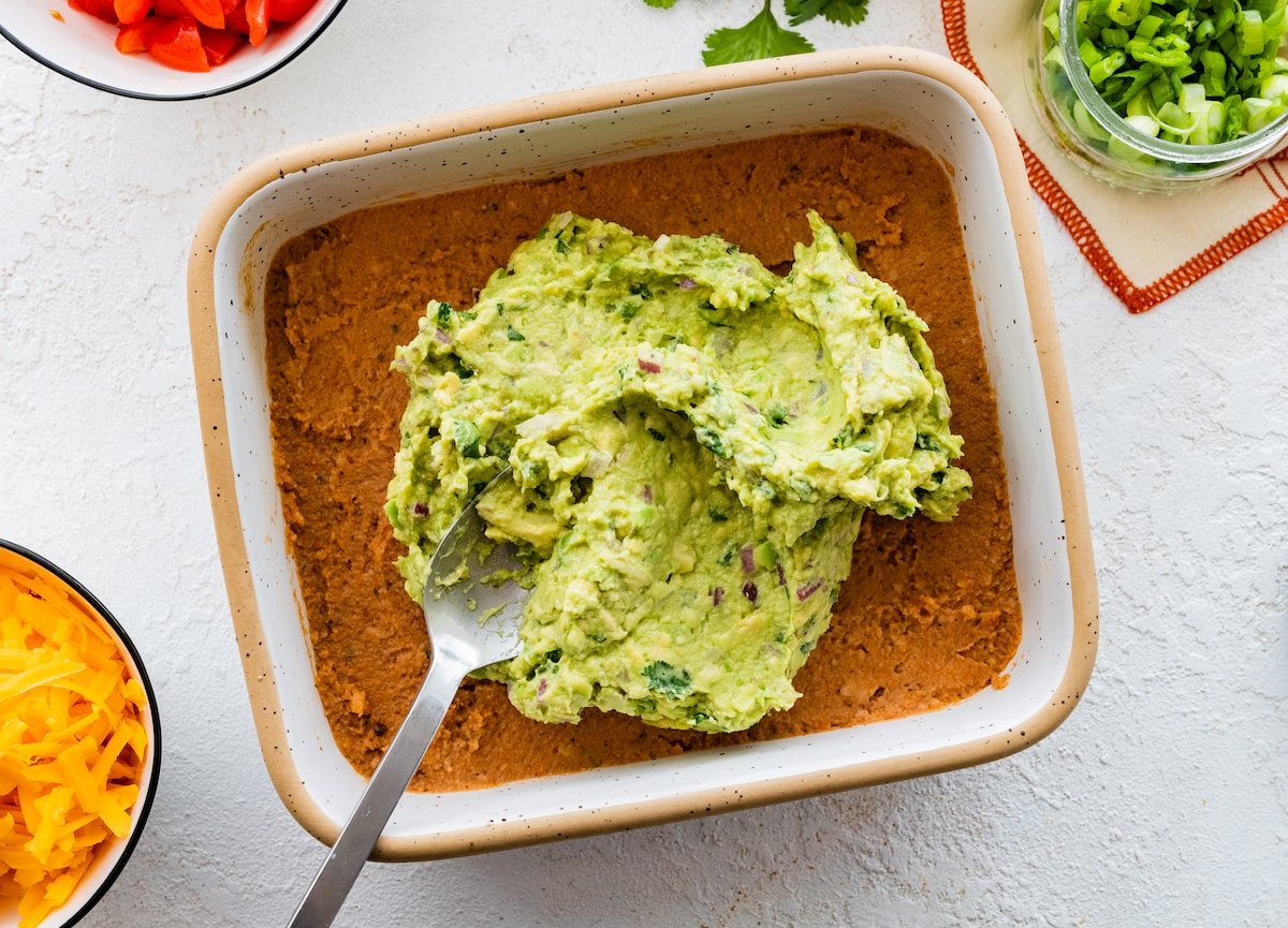 a layer of refried beans and guacamole in dish to make 7 layer dip. 