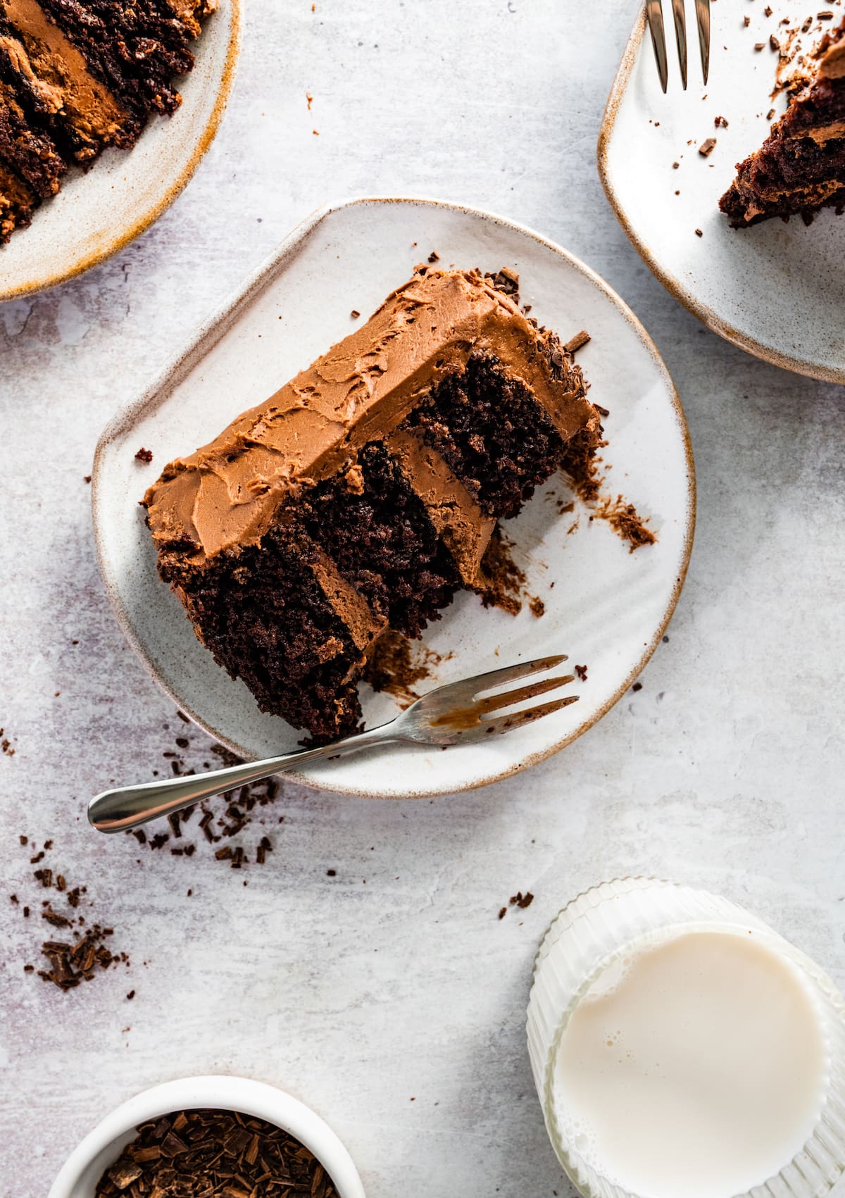 piece of chocolate cake with chocolate frosting on plate with fork. 