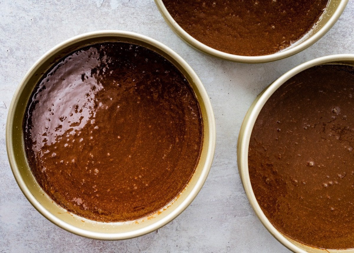 chocolate cake batter in cake pans. 