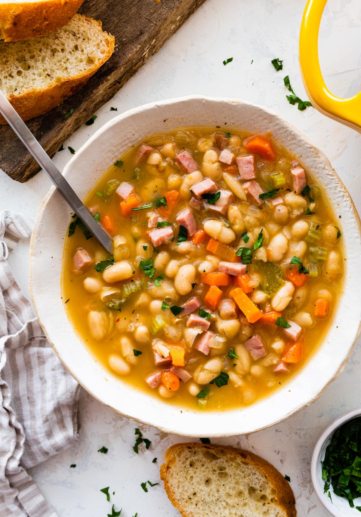 ham and bean soup in white bowl with spoon. 