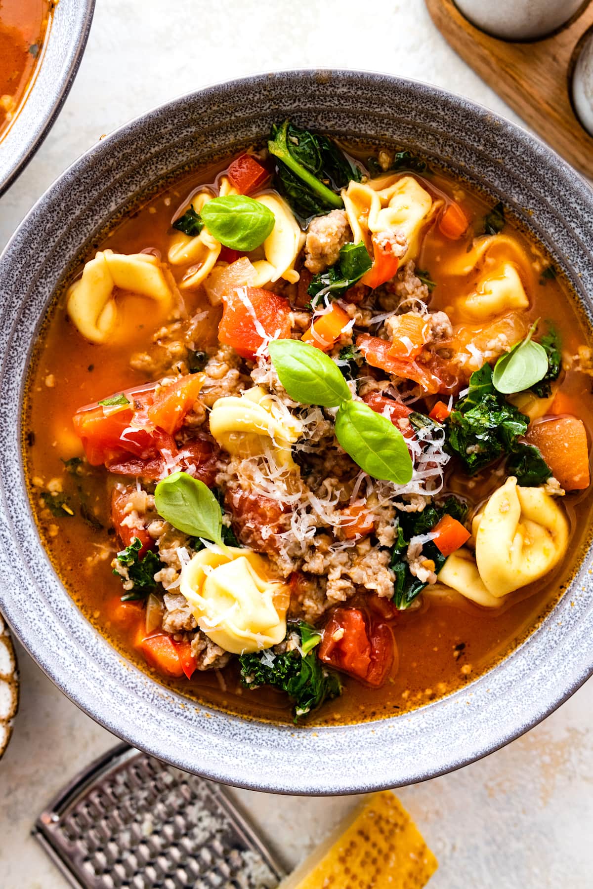 Italian sausage tortellini soup in bowl with Parmesan cheese. 