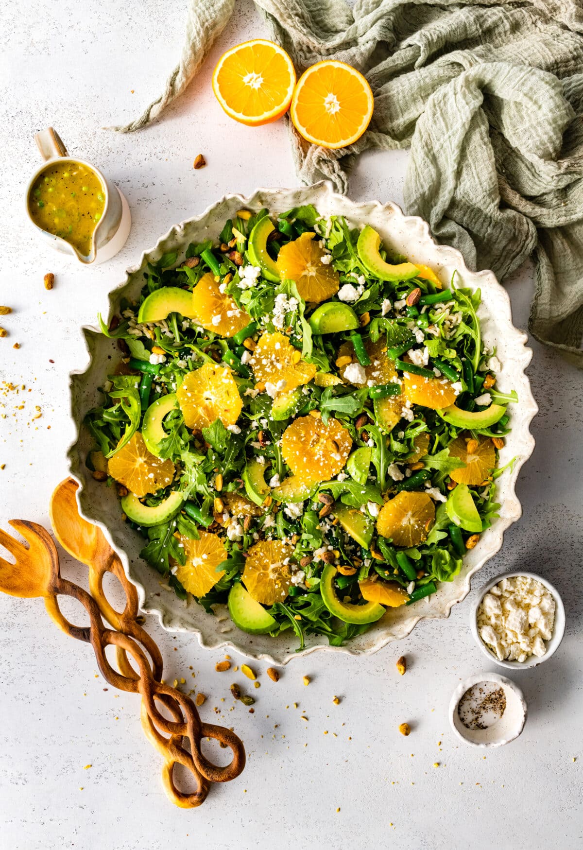 orange arugula salad in serving bowl with wood salad servers. 