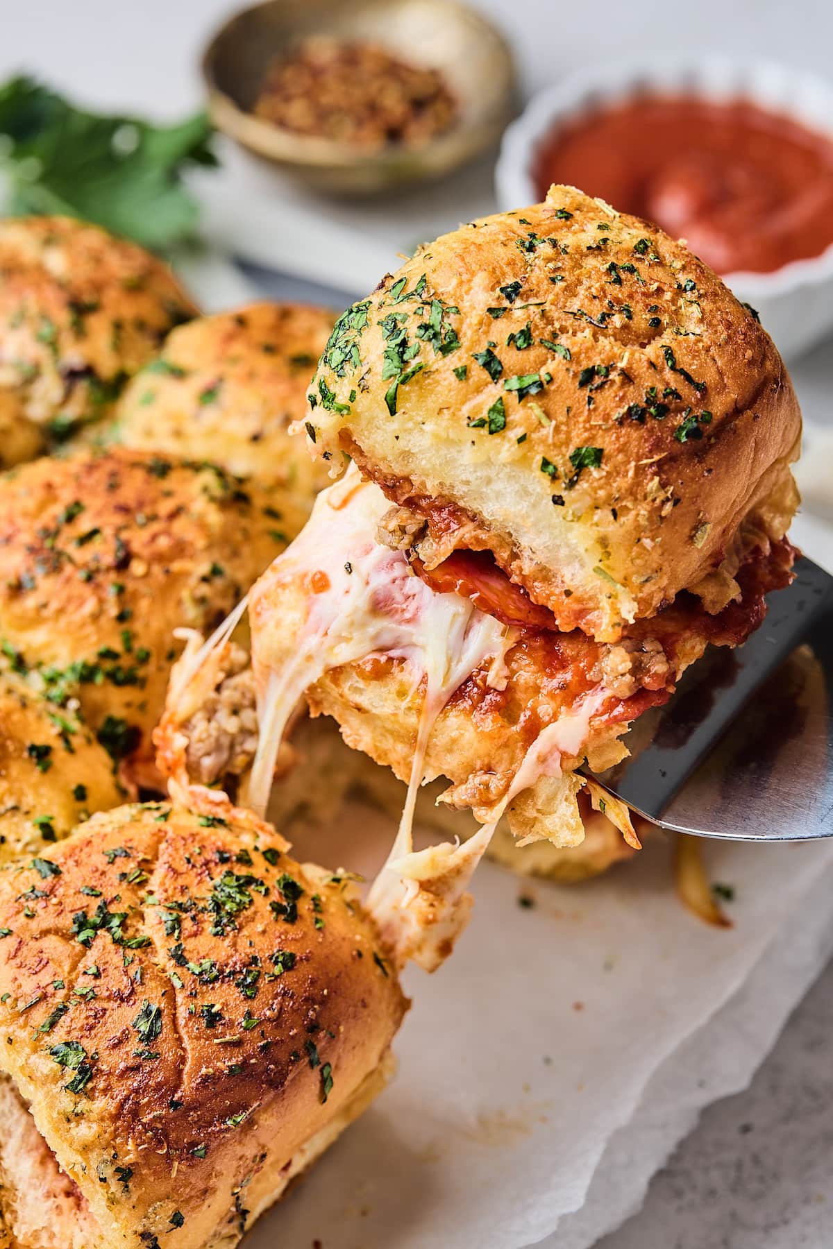 pizza slider being lifted out of pan with melty cheese and garlic butter top. 