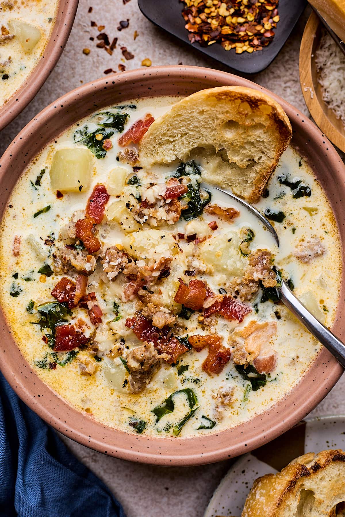 zuppa toscana soup in bowl with spoon and crusty bread. 