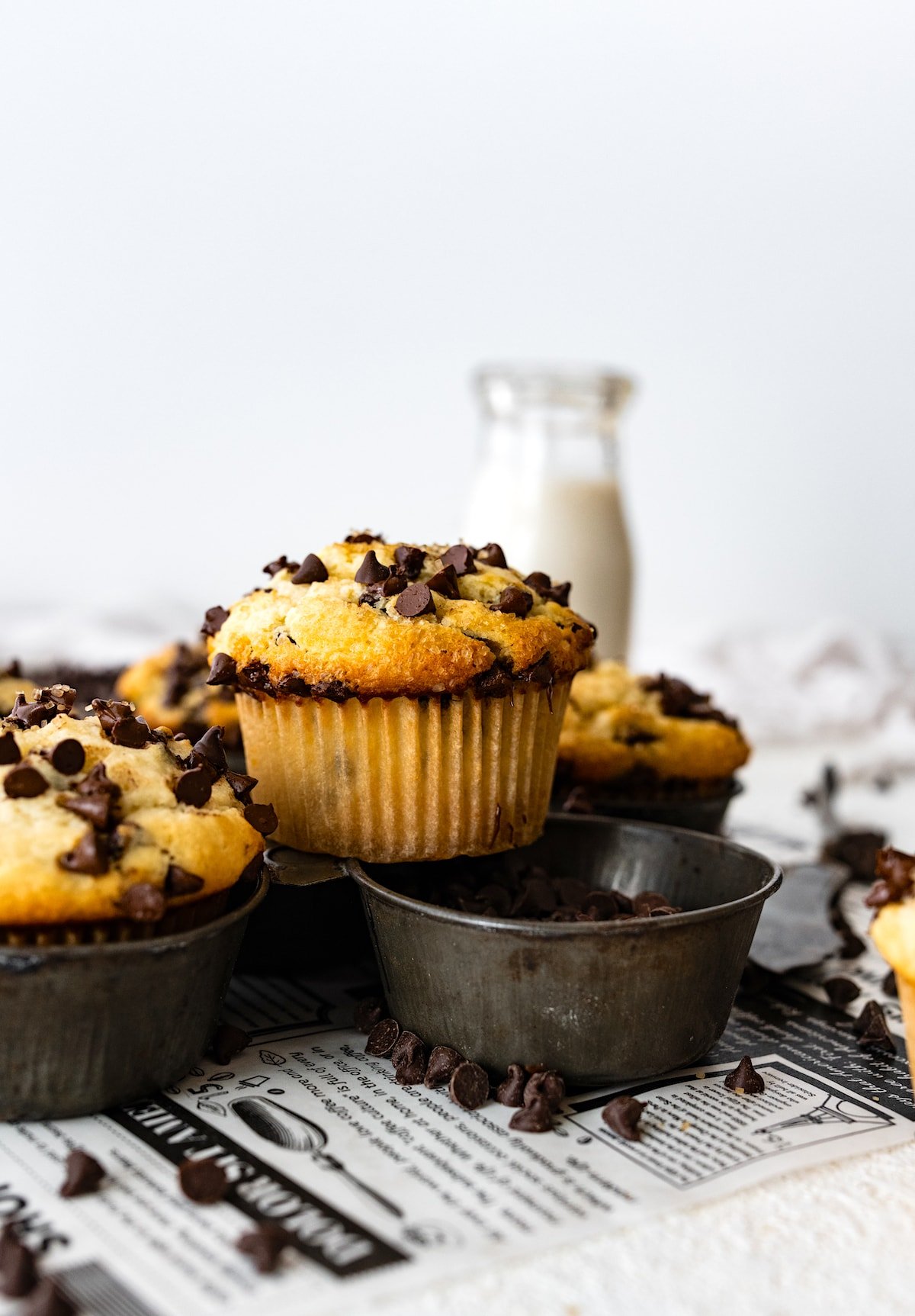 chocolate chip muffin sitting on top of muffin tin with mini chocolate chips. 