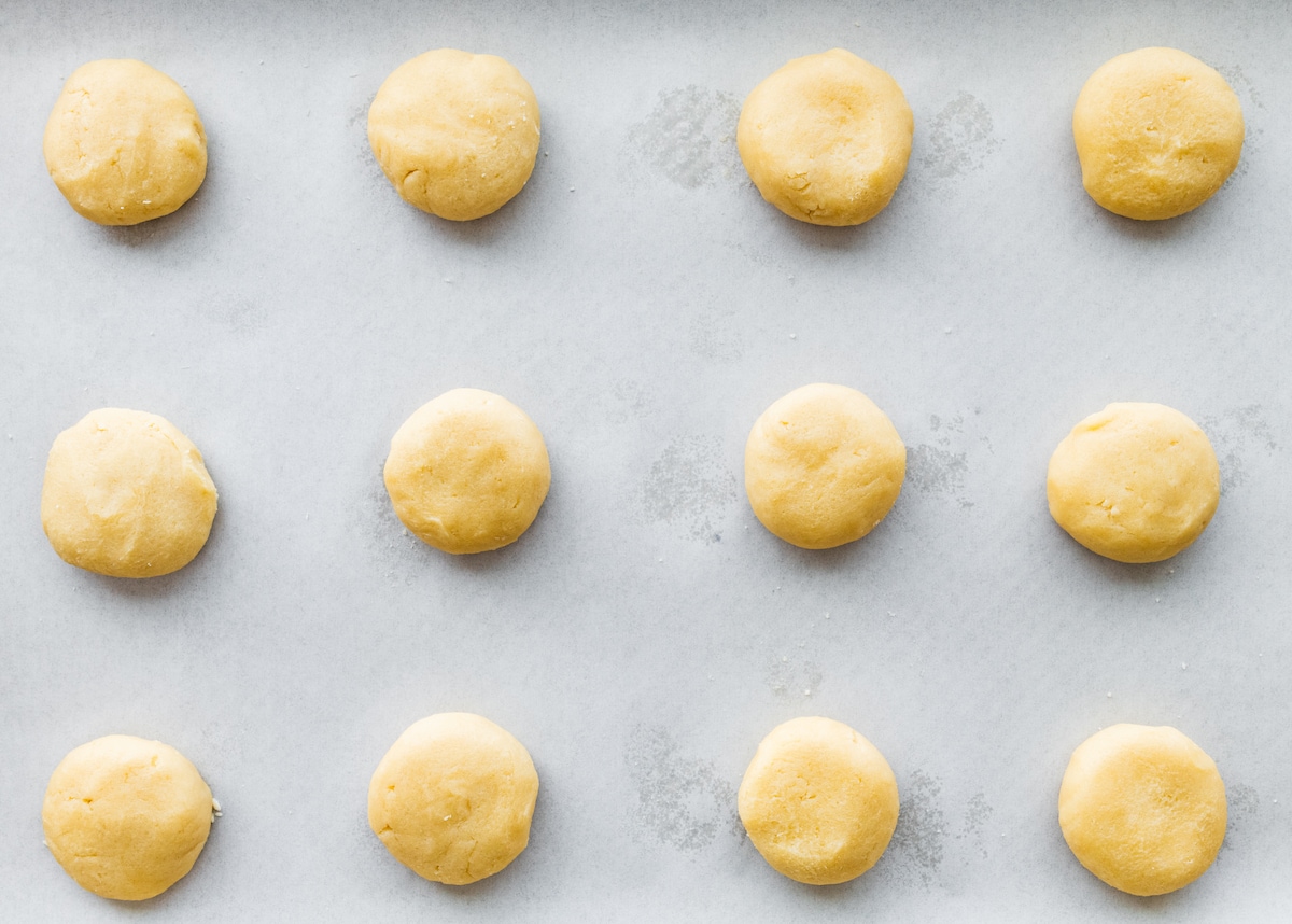 almond cookie dough balls on baking sheet with parchment paper. 
