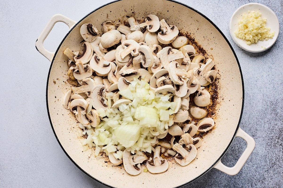 mushrooms and onion cooking in skillet to make beef stroganoff. 
