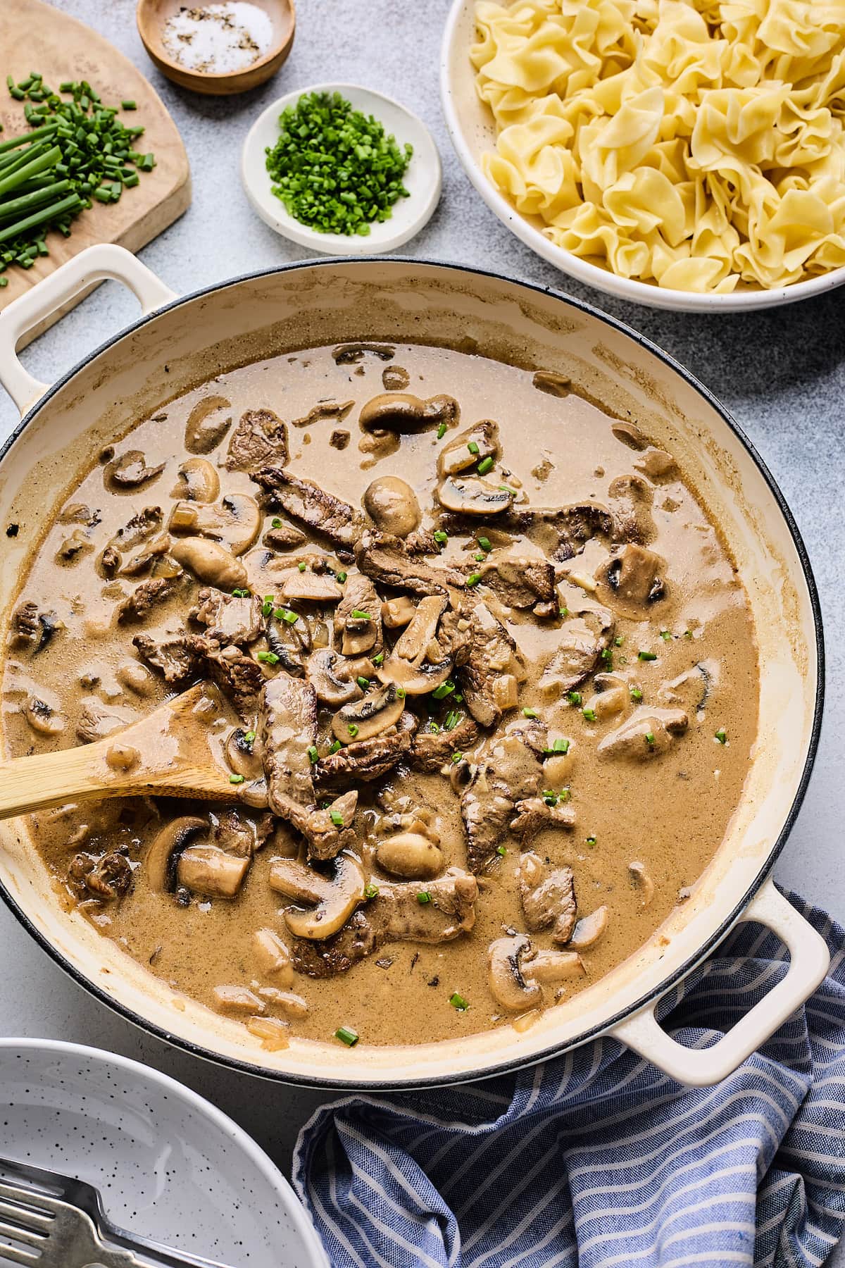 beef stroganoff in skillet with wooden spoon.