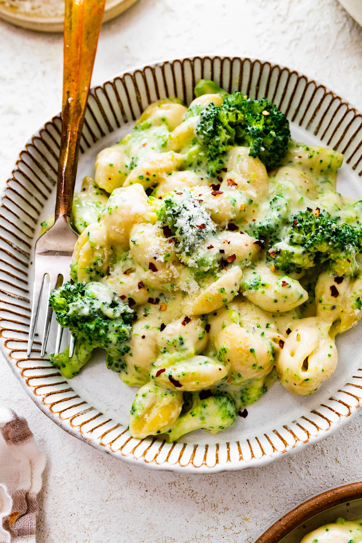 close up of broccoli mac and cheese on plate with fork. 