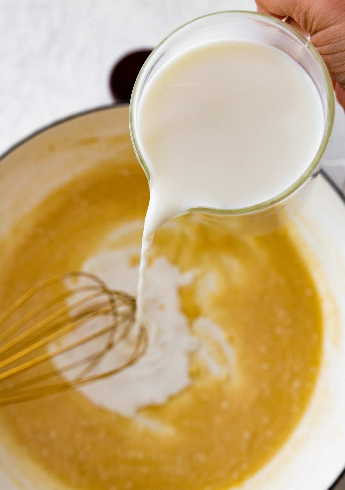pouring milk into roux in pot. 