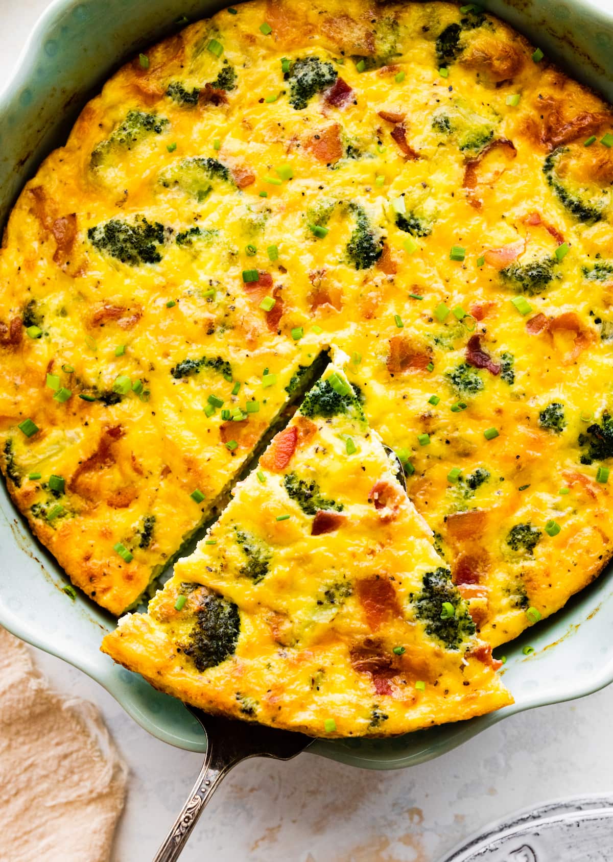 piece of crustless quiche being cut in pie pan. 