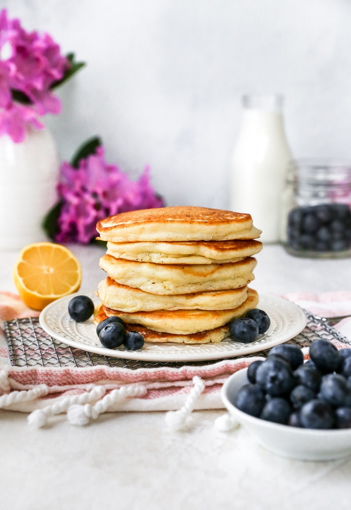 stack of lemon ricotta pancakes on plate with fresh blueberries. 