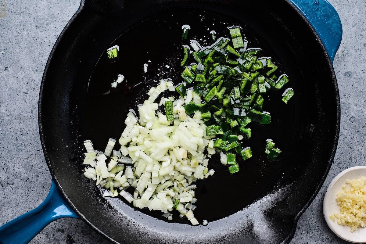 onion and poblano pepper cooking in oil in cast iron skillet. 
