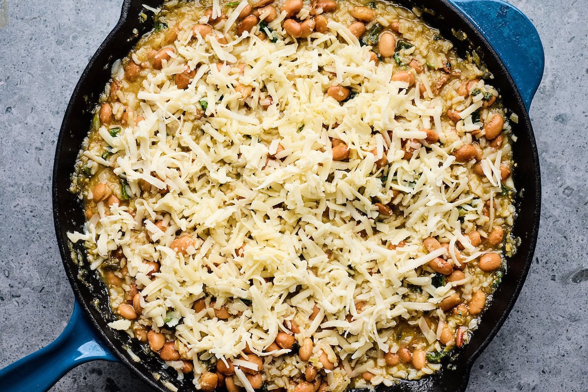 rice and beans in skillet with shredded cheese on top. 